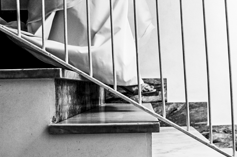 Detail of woman’s foot with wedding dress descending stairs, close up of bride walking down stairs