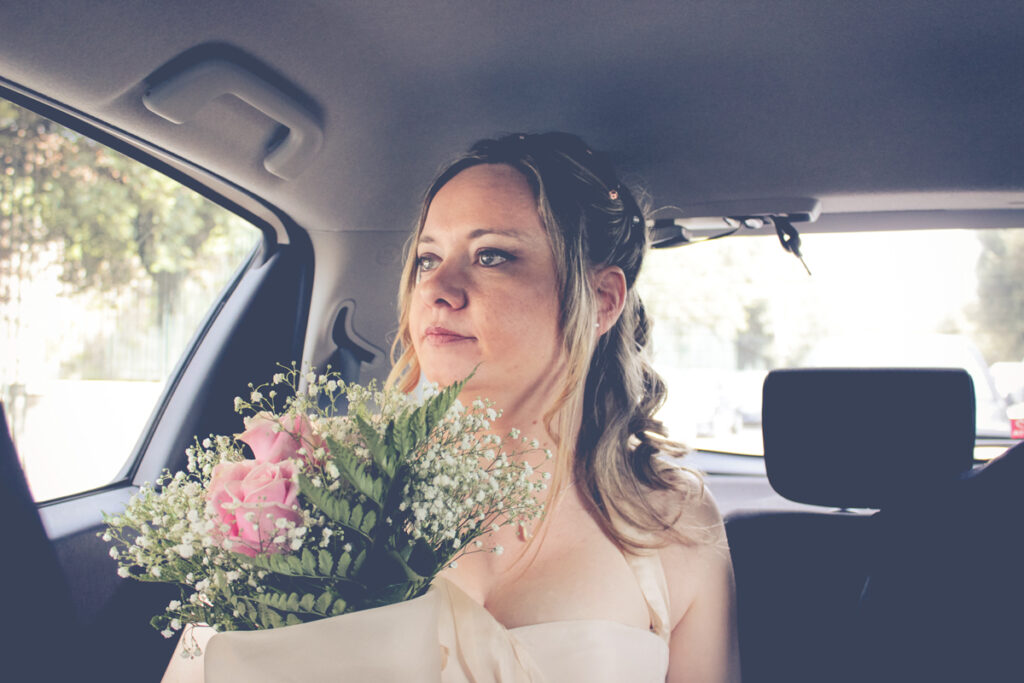 The bride in the car with dreamy look while reaching her future husband 