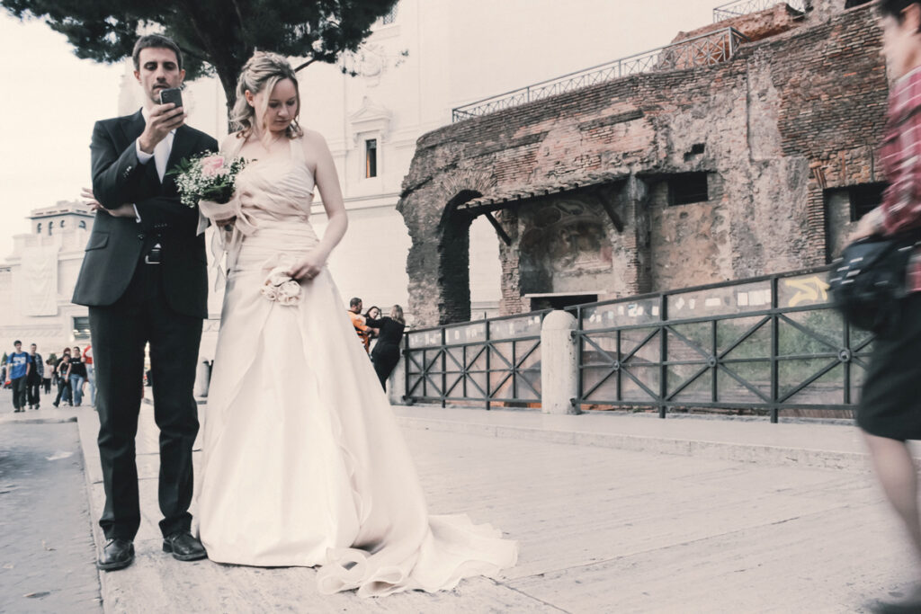 Urban wedding photo, the newlyweds waiting for the car in Rome streets