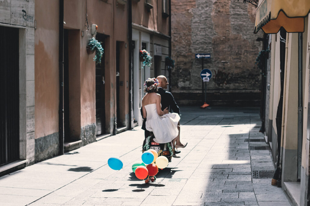 The couple goes for a ride in a scooter with colorful baloons