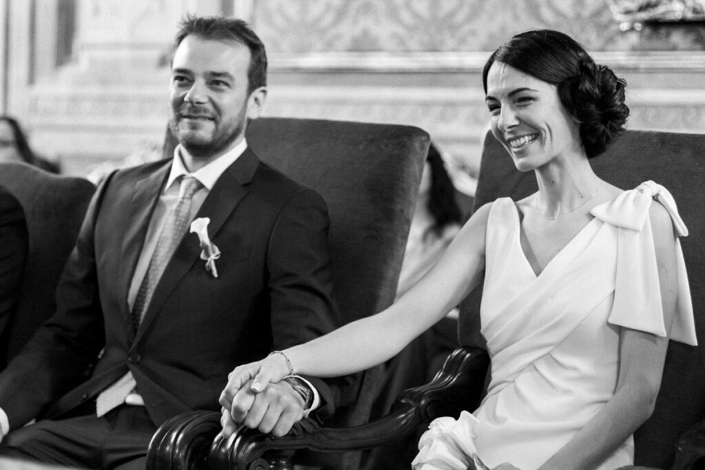 Excited bride and groom hold hands during the wedding ceremony