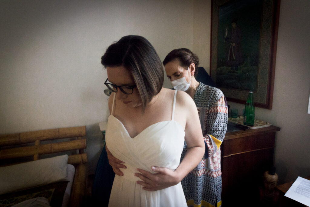 Young bride preparing, mother checking the wedding dress