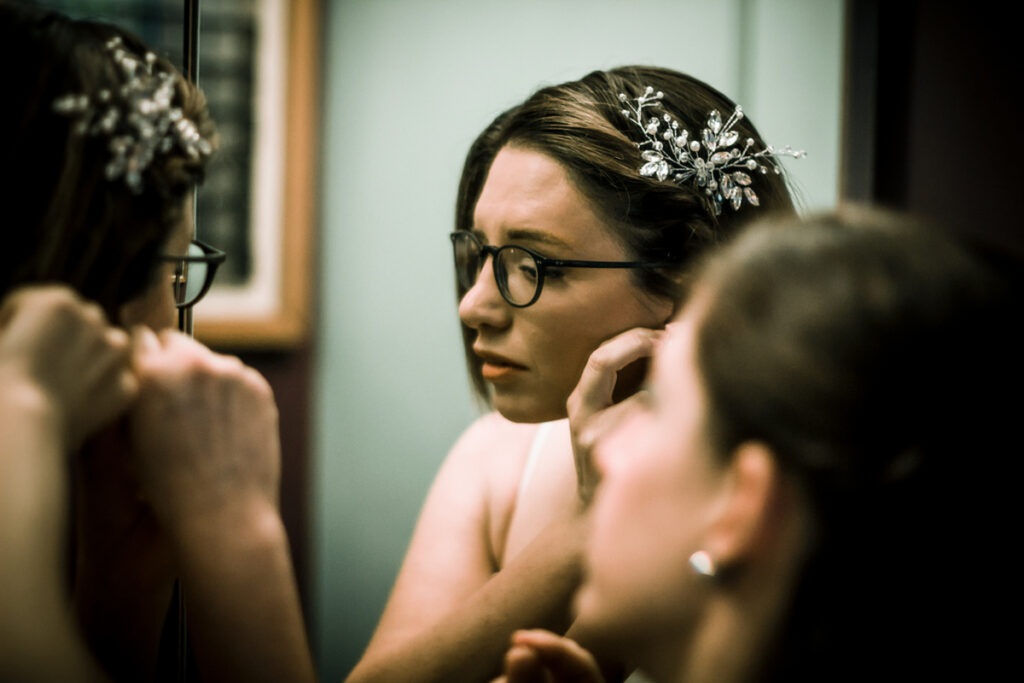 young bride looks at the mirror during the preparation with friends helping her