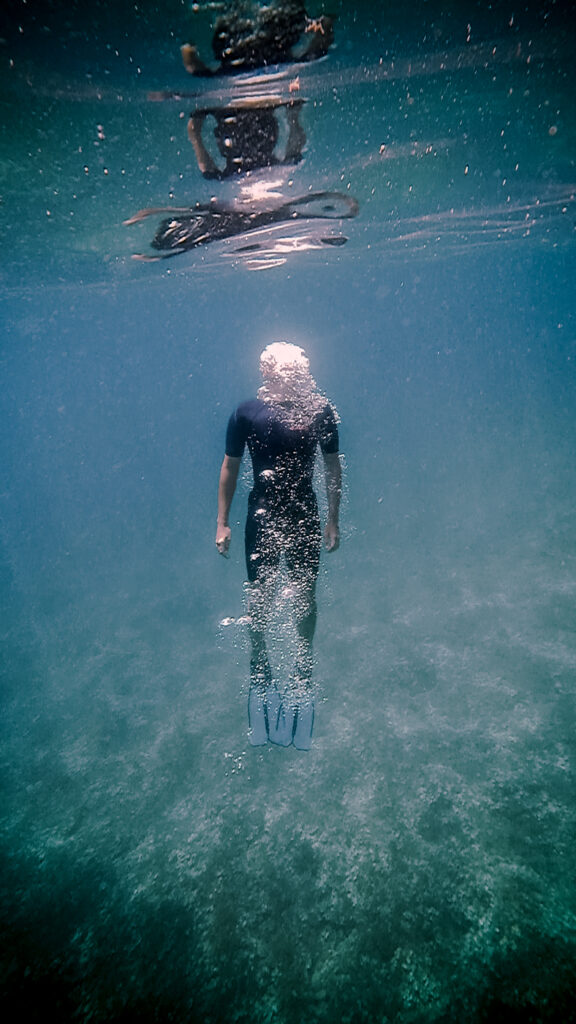 A man diving on the blue ocean, man and bubbles in the water