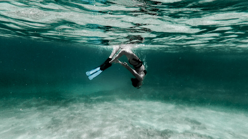 a woman doing stunts in water, underwater