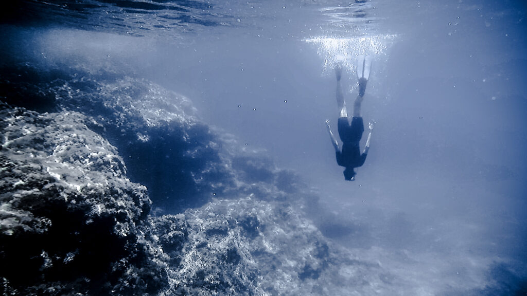 a woman diving upside down in the ocean, walking on the surface of the sea