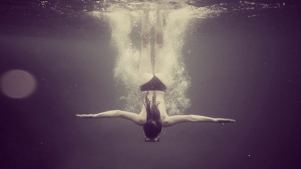 woman diving on the deep and purple water, underwater